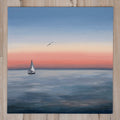 Sailing boat on a calm sea with a bird flying above, set against a sunset sky.