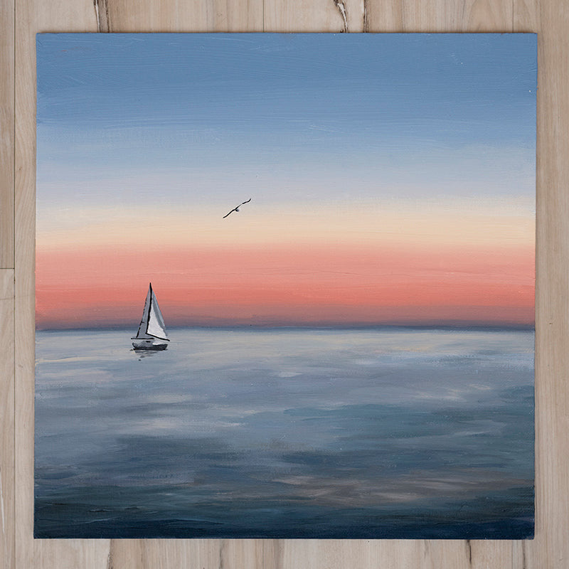 Sailing boat on a calm sea with a bird flying above, set against a sunset sky.